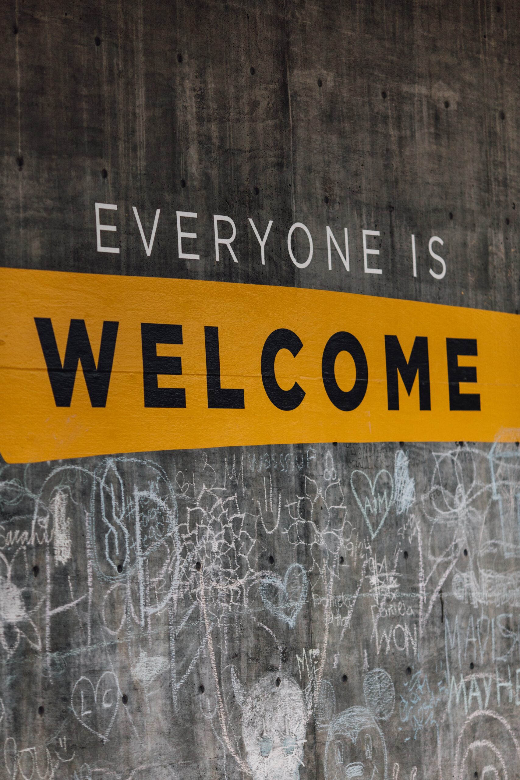 Wall with 'Everyone is Welcome' message in bold yellow and black, surrounded by chalk doodles symbolizing inclusivity and diversity. Professional CV Services 