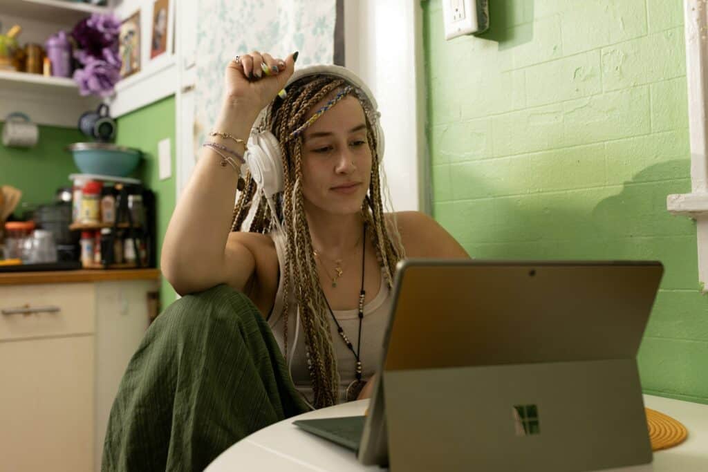 A young student with braided hair and headphones studying at home on a laptop, symbolizing flexible learning and career preparation with CV4Students.