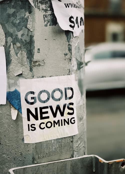 Bold poster with the words 'GOOD NEWS IS COMING' pasted on a weathered concrete pole, symbolizing positive opportunities ahead for students and immigrants. CV Testimonials