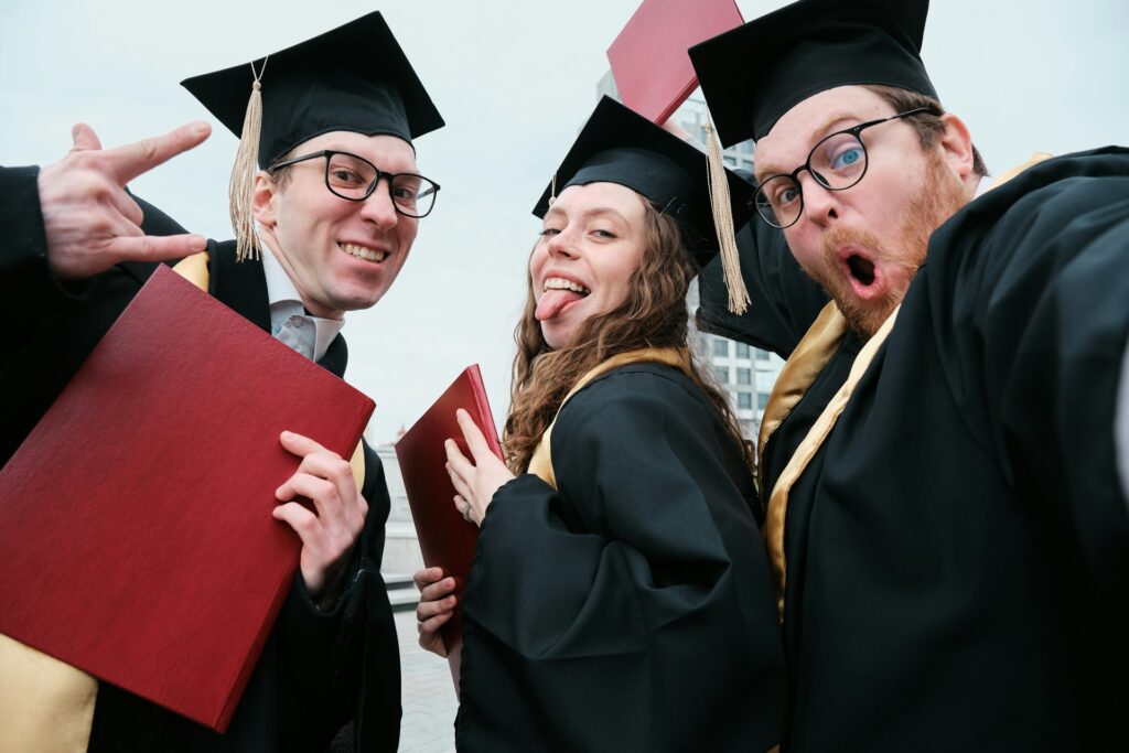 Group of excited graduates in caps and gowns celebrating with diplomas, showcasing joy and success for students and graduates.