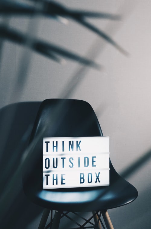 Think Outside The Box sign placed on a modern black chair, encouraging students, school leavers, and immigrants to approach career opportunities creatively with CV4Students. Professional industry organizations. Immigrant Services. | Resources for Immigrants