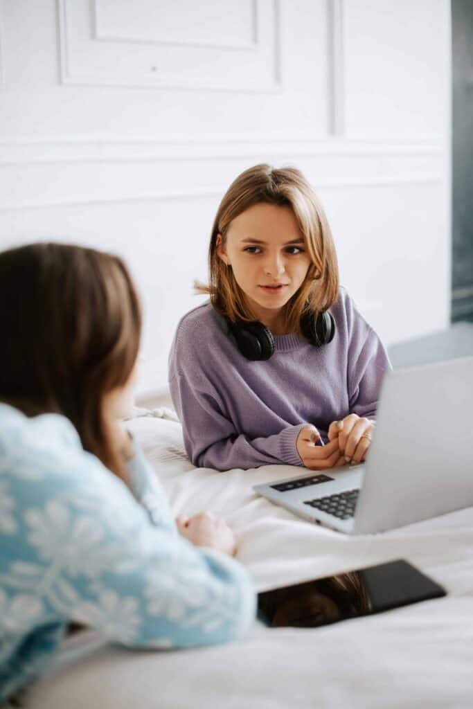 Two young students preparing for a job interview, discussing resumes and career strategies on a laptop