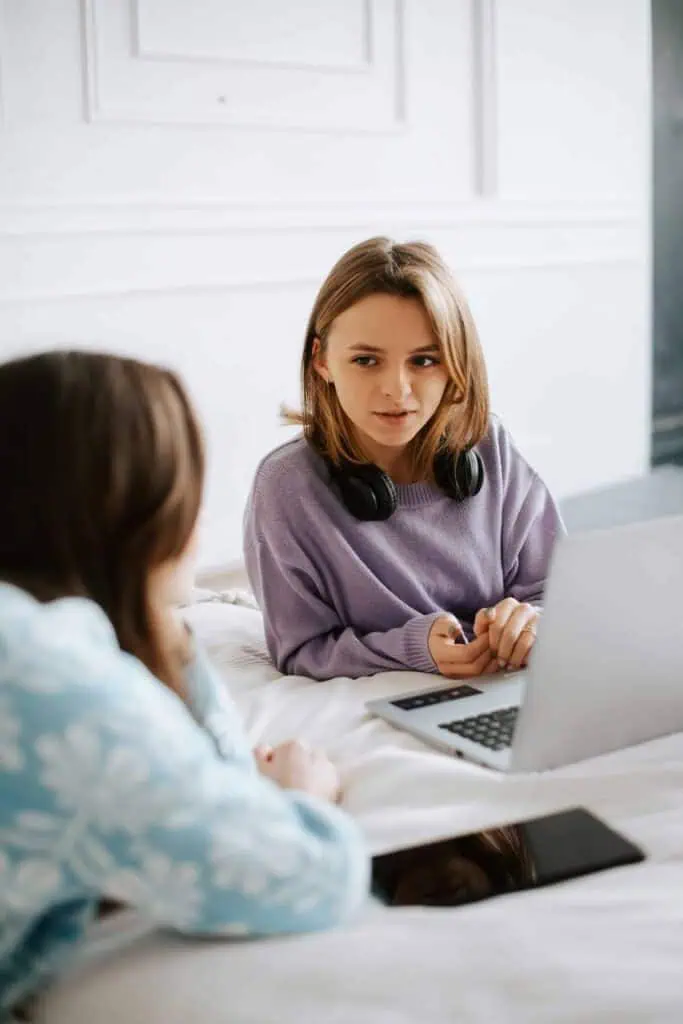 Two young students preparing for a job interview, discussing resumes and career strategies on a laptop