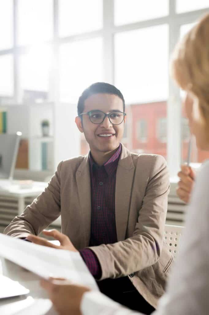 Confident young immifrant in a job interview, engaging with the recruiter in a bright and modern office.
