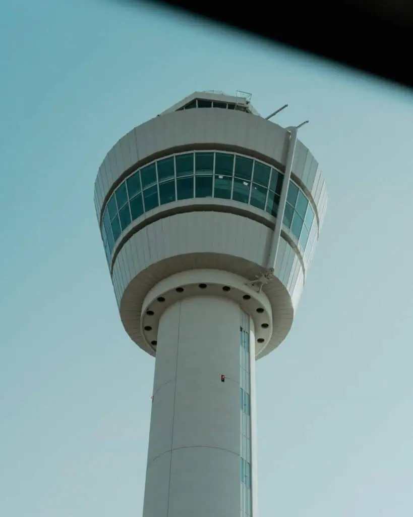 Modern air traffic control tower under a clear sky, symbolizing aviation safety and career in air navigation services.