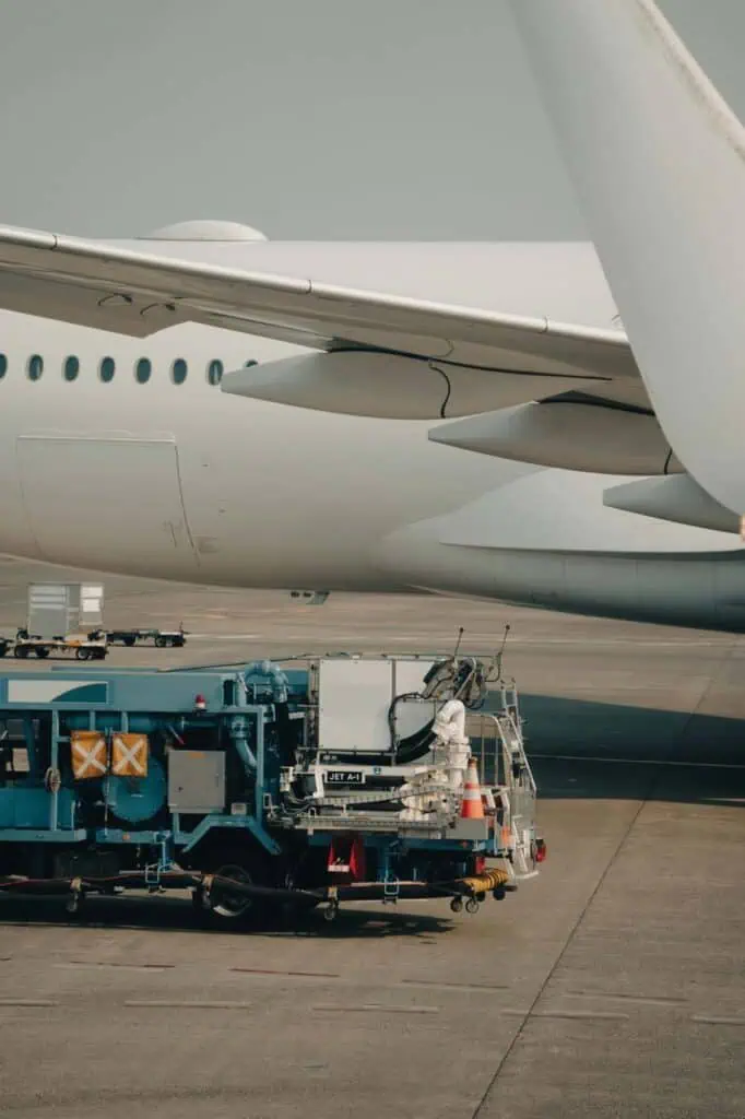 Aircraft refueling technician operating fuel truck next to commercial airplane on airport tarmac