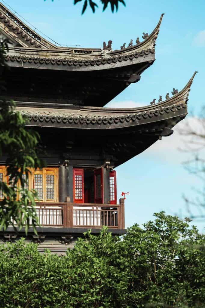 A traditional Asian pagoda with curved rooftops, intricate wooden details, and red window shutters, symbolizing cultural heritage and the immigrant journey