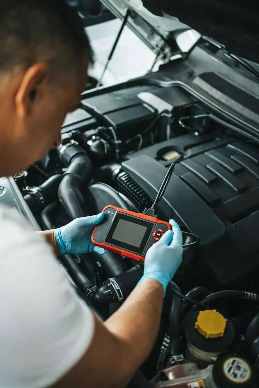 Automotive electrician diagnosing car engine using electronic diagnostic tool
