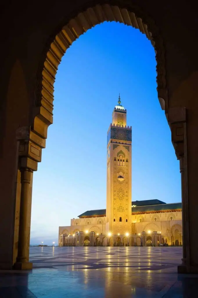 The stunning Hassan II Mosque in Casablanca, Morocco, framed by a traditional arch at dusk—symbolizing ambition, excellence, and the journey to success, just like building your resume for a brighter future.