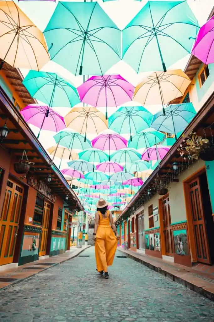 Colorful street in Colombia with a woman walking under vibrant umbrellas, symbolizing new career opportunities and exploration.