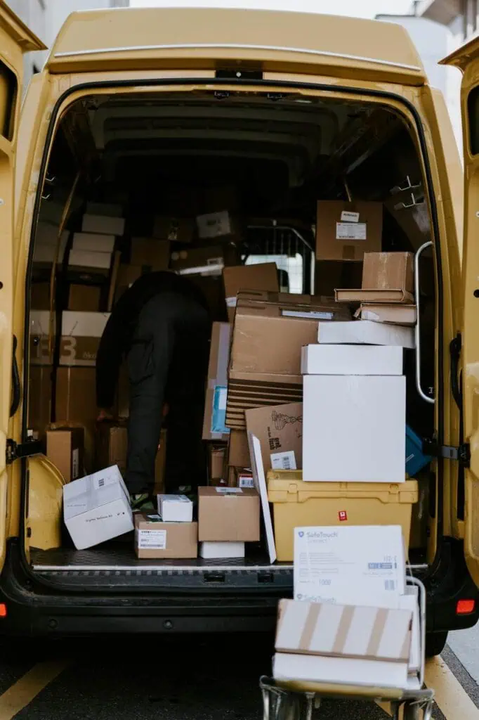 Courier loading delivery van filled with parcels and packages for distribution