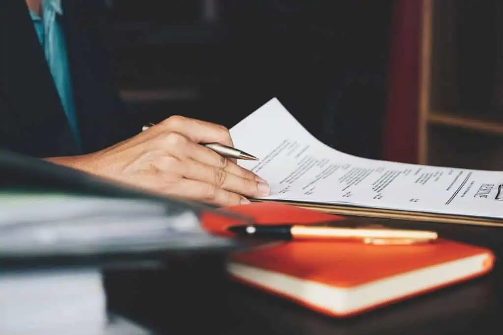 Employer reviewing a candidate’s CV with a pen in hand, emphasizing the importance of a strong resume for job applications.
