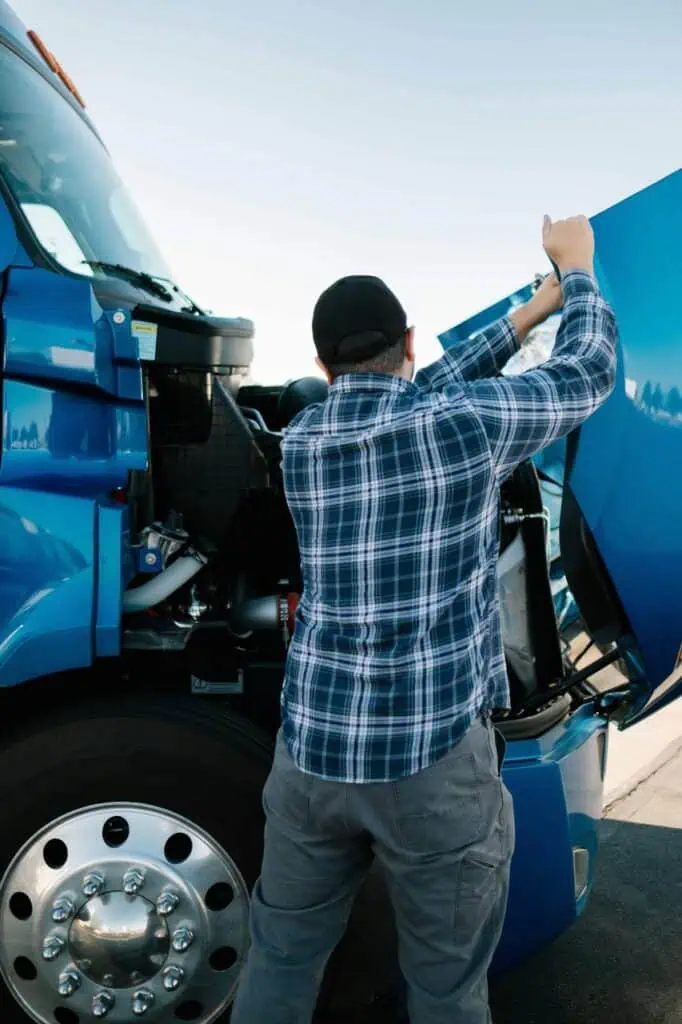 Diesel mechanic inspecting semi-truck engine at roadside