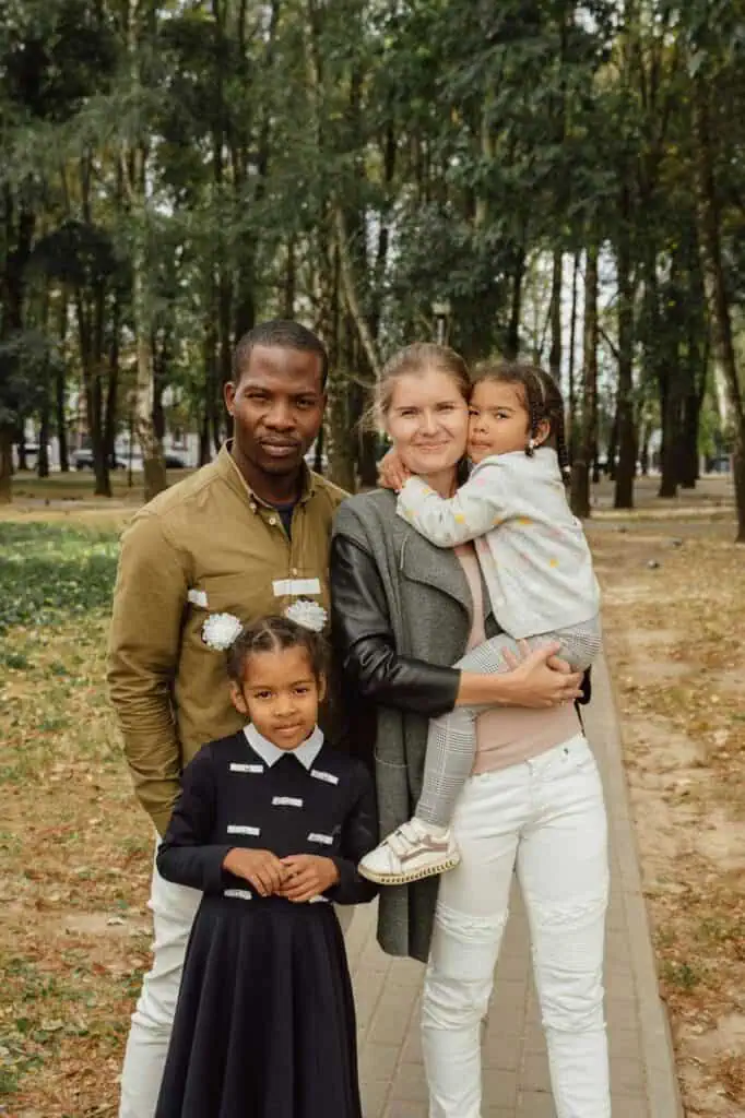 A loving family of four posing outdoors in a park, symbolizing their journey as immigrants from the Dominican Republic.