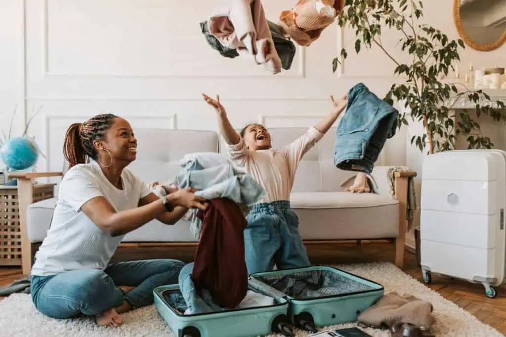 An Algerian family packing a suitcase together, with clothes flying in the air in a joyful home setting
