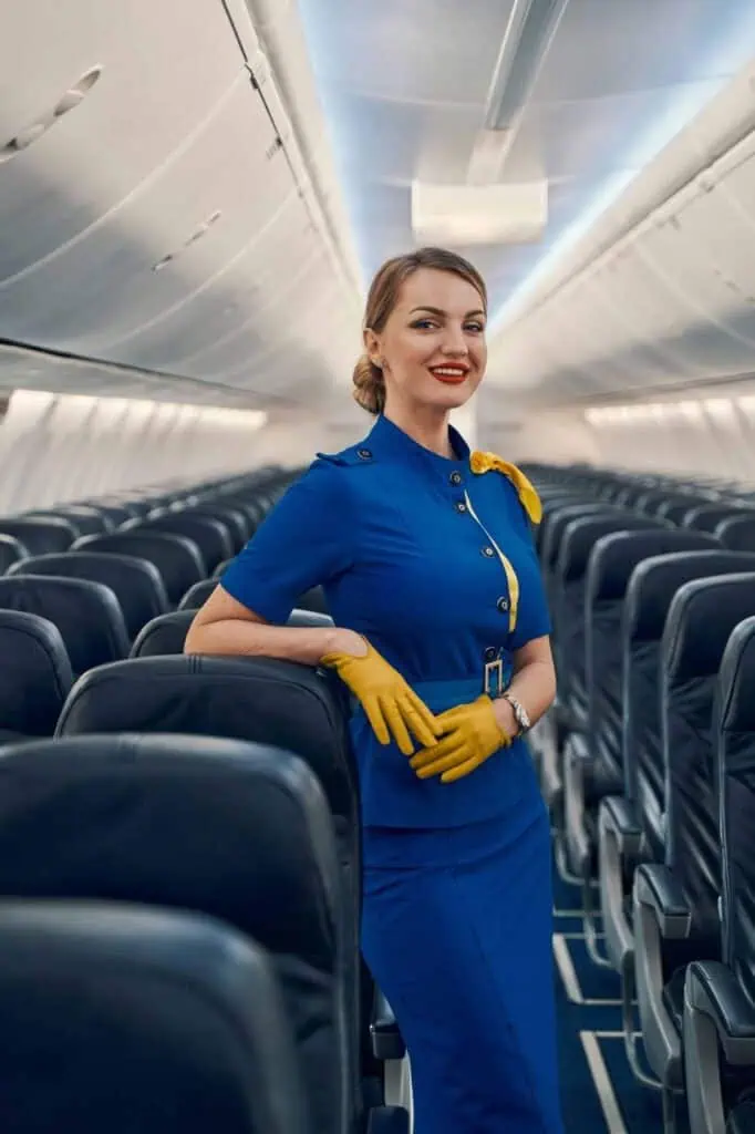 Flight attendant standing in airplane cabin with professional uniform