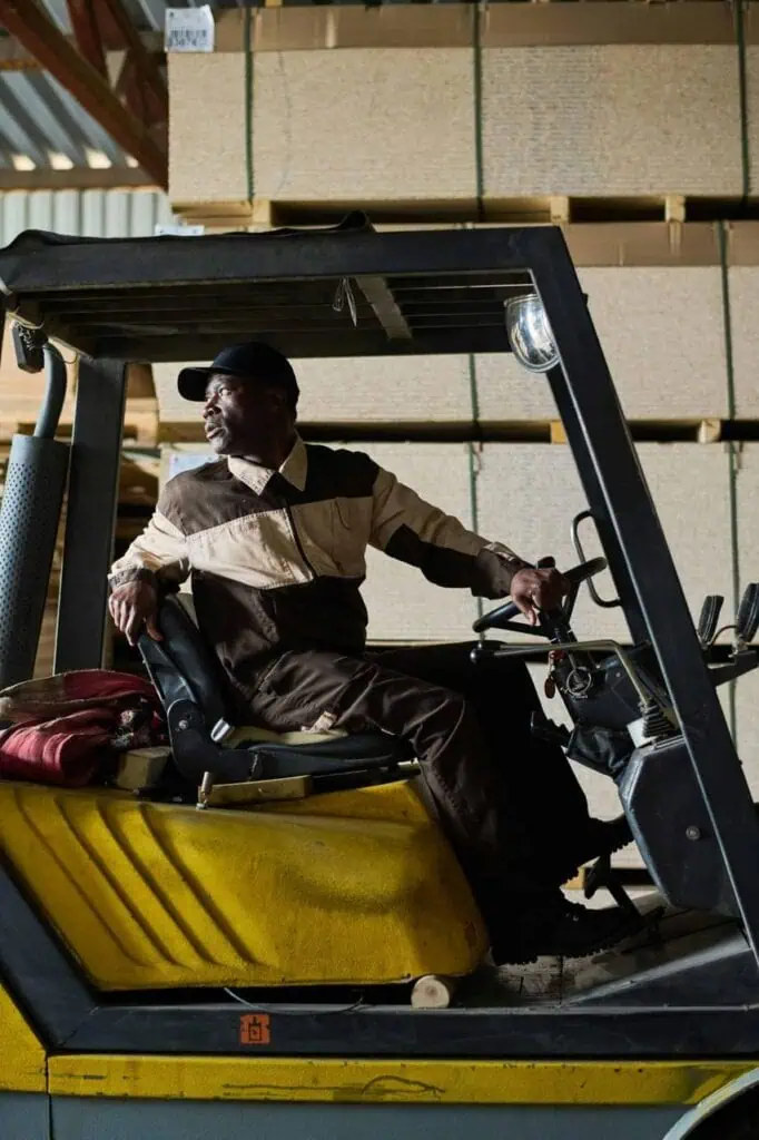 Forklift operator navigating warehouse with stacked pallets