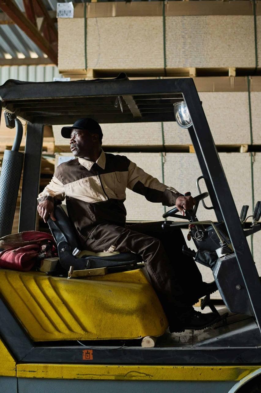 Forklift operator navigating warehouse with stacked pallets