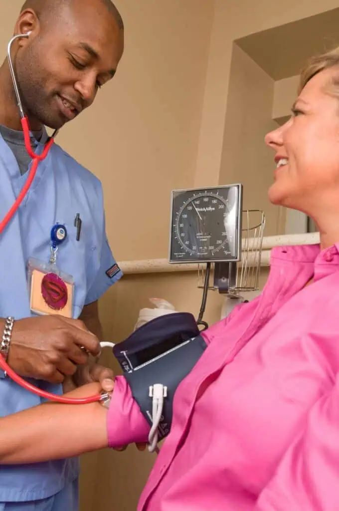 A friendly healthcare professional measuring a patient's blood pressure, representing quality care and community health services.