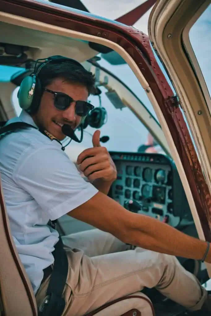 Helicopter pilot giving thumbs-up while seated in cockpit with headset