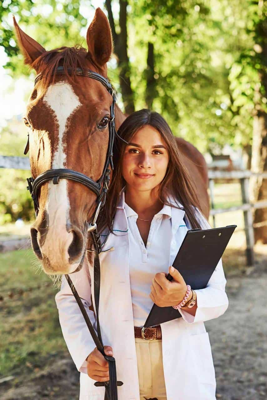 Female livestock veterinarian standing beside a horse, representing careers in animal health.