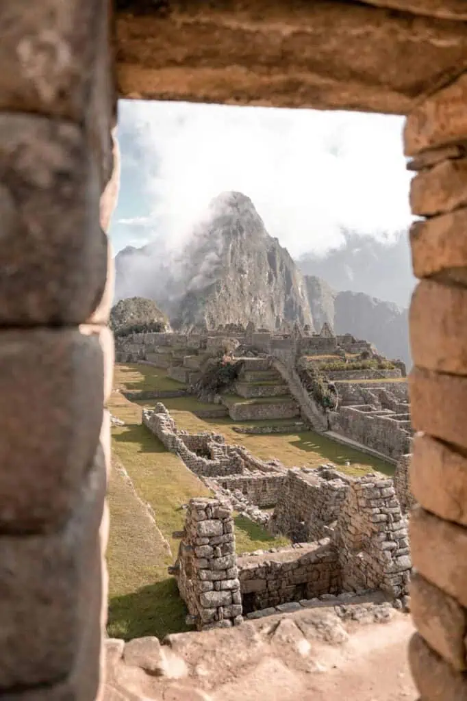 Ancient ruins of Machu Picchu framed by a stone window, showcasing Peru's rich history and culture.