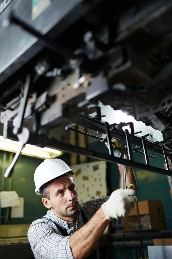Marine engineer in hard hat performing maintenance on ship engine system