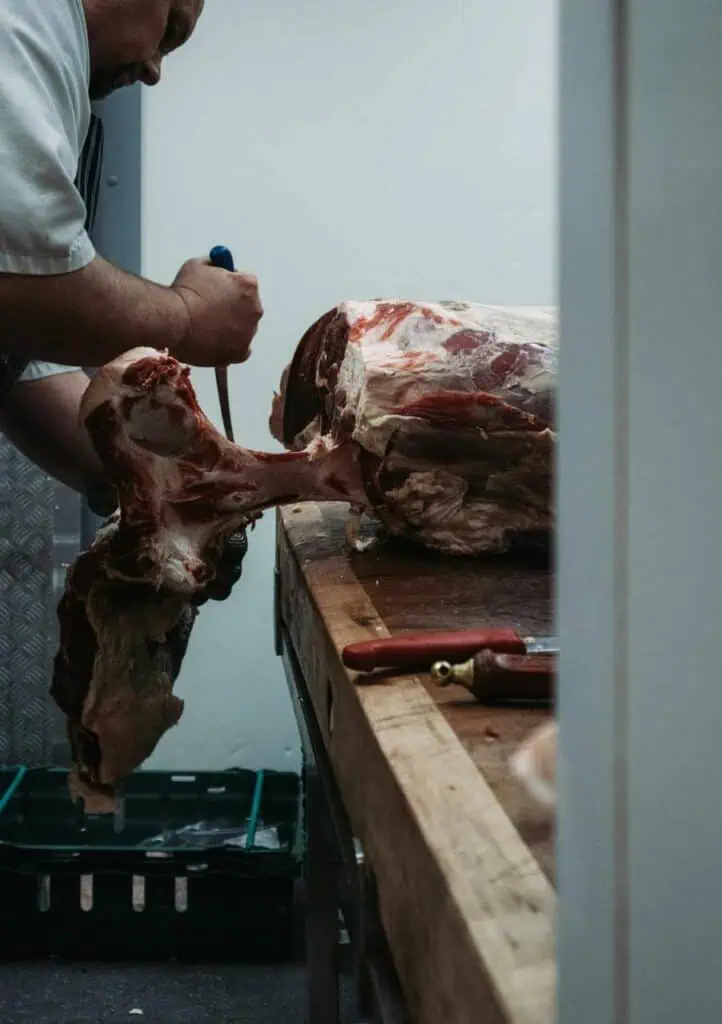 A skilled meat processor cutting and preparing fresh meat in a butchery, highlighting career opportunities in food processing and meat production.