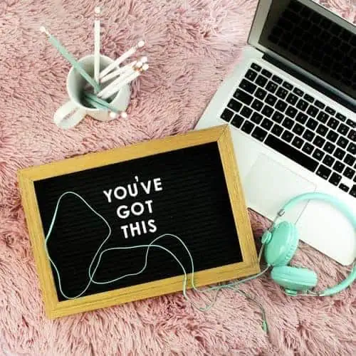 A motivational letter board reading "You've Got This," placed on a fluffy pink rug, with a laptop, mint green headphones, and a cup of pencils nearby | CV creation process
