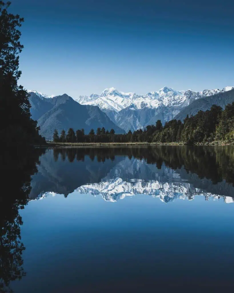 Stunning New Zealand mountain range reflected in a lake, symbolizing new opportunities for immigrants and students.