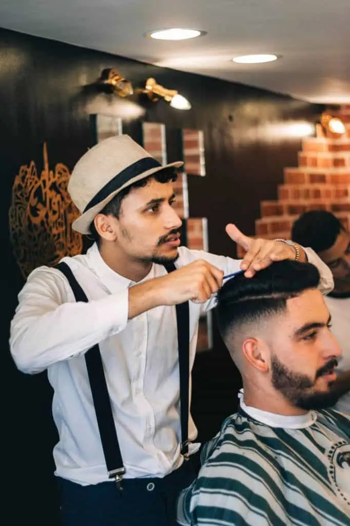 A skilled barber styling a client's hair in a modern barbershop, showcasing expertise and career opportunities in personal care services