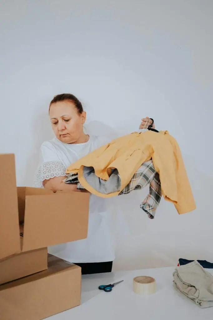 Warehouse pick and pack worker sorting clothes into cardboard shipping boxes