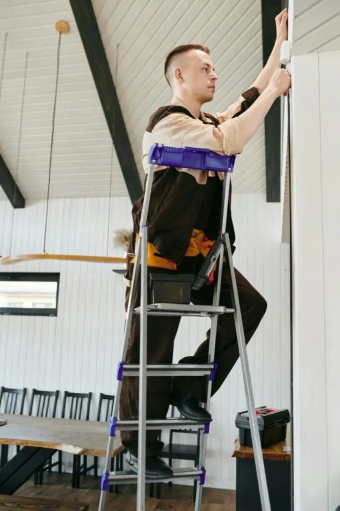 School caretaker performing maintenance work on a ladder inside an educational facility