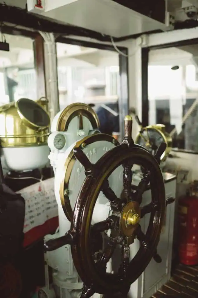Wooden ship wheel in control room of a maritime vessel, symbolizing ship captain duties