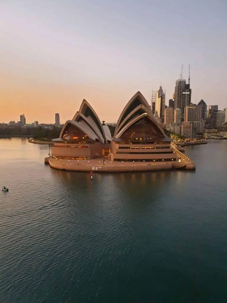 The Sydney Opera House at dusk, with city lights reflecting on the water, representing the vibrant culture and lifestyle of Australia.