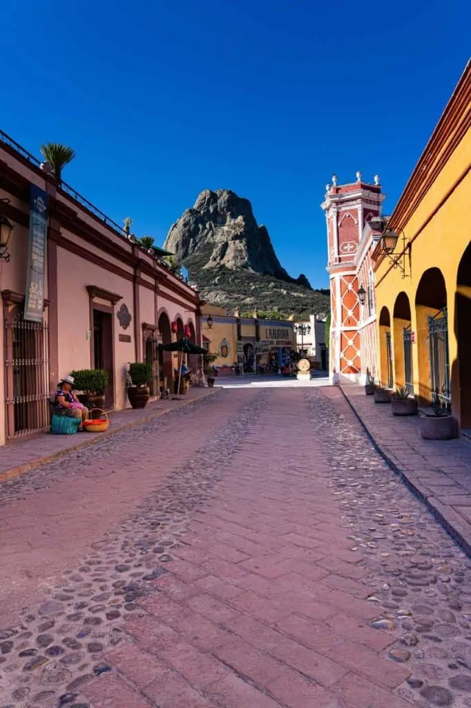 A colorful street in Bernal, Mexico, with a view of Peña de Bernal, showcasing the country’s rich history and culture.