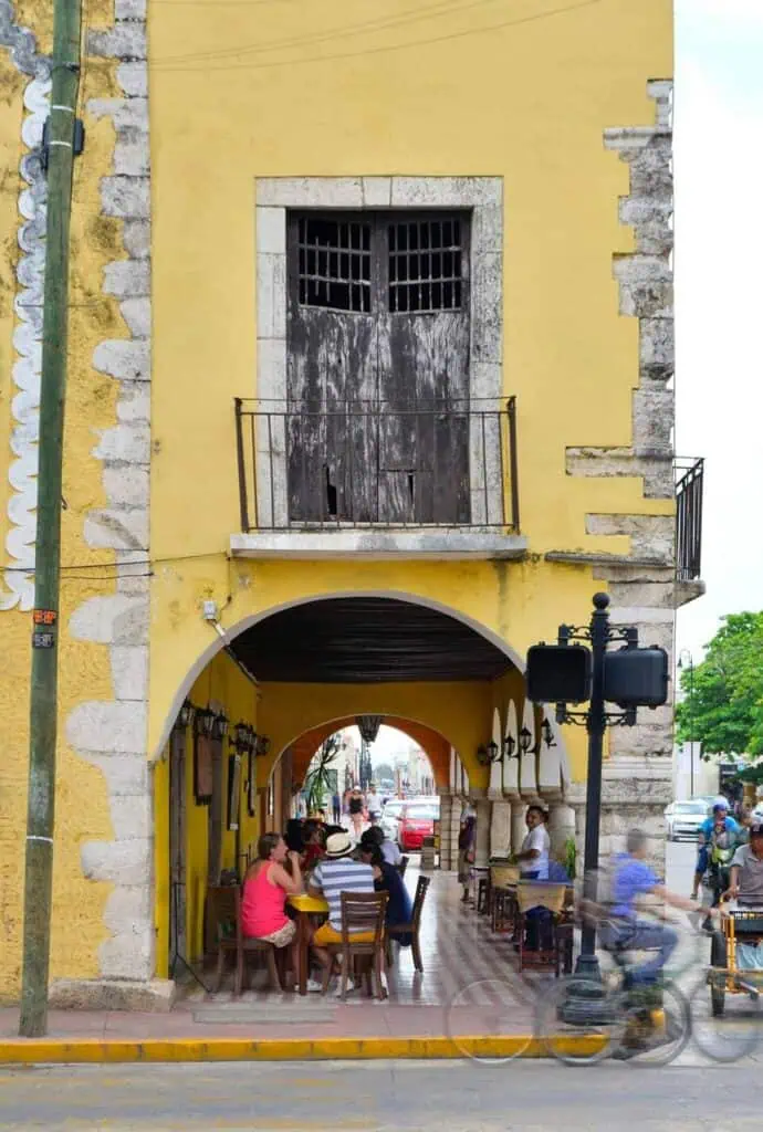 Historic yellow building with an open-air café in a bustling Latin American city, symbolizing culture, education, and career opportunities.