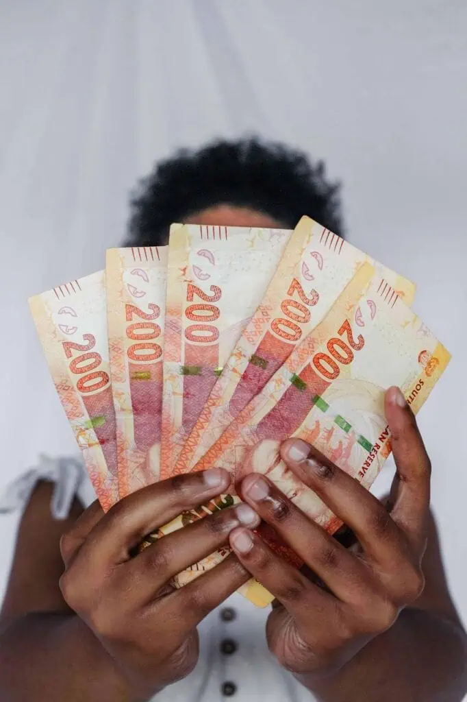 Person holding a fan of South African Rand banknotes, representing wages, salary growth, and financial success.