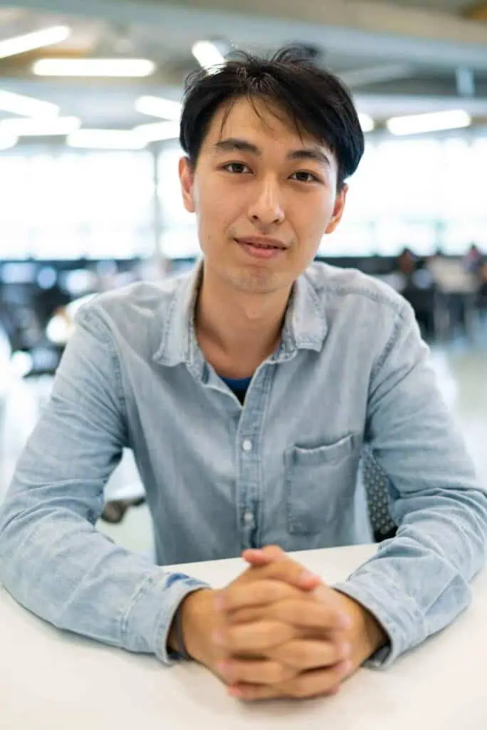 A young confident Chinese Student in Modern Study Workspace