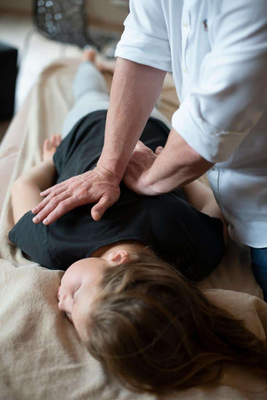 Immigrant receiving chiropractic treatment on a therapy table, symbolizing hands-on healthcare training and career opportunities in chiropractic care.