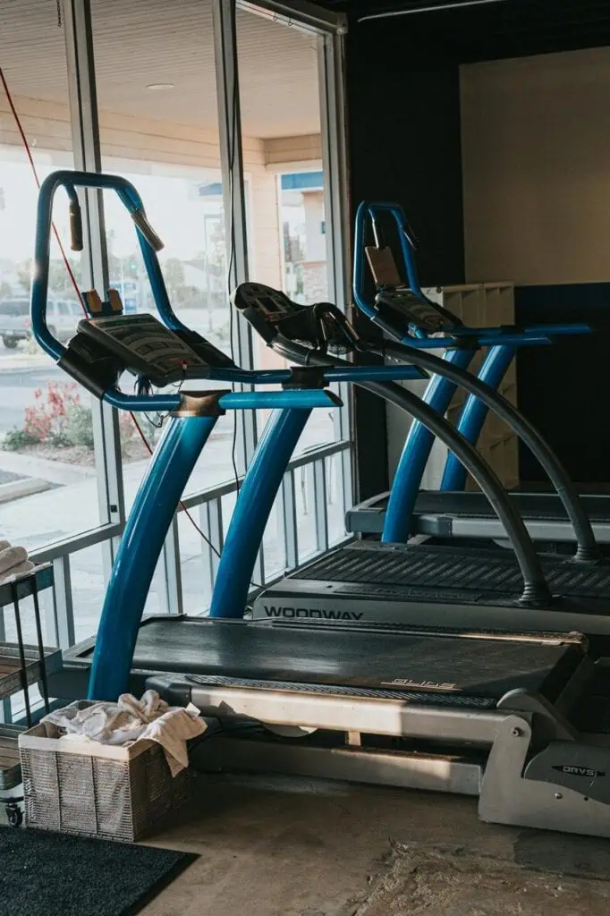 Treadmills in a gym setting, awaiting inspection and servicing by a fitness equipment maintenance technician to ensure optimal performance and safety.