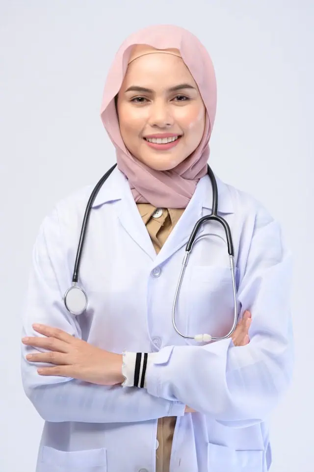 A smiling female gastroenterologist wearing a hijab and white coat with a stethoscope, ready to support patients with digestive health care.