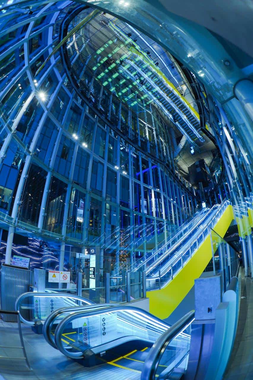 Modern illuminated escalators and lifts in a glass hotel atrium – career image for elevator and escalator technician roles.