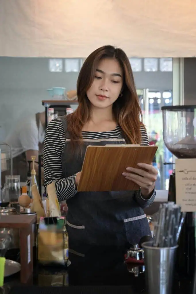 Restaurant manager reviewing inventory or orders behind the counter—representing leadership and operational roles in food service careers.
