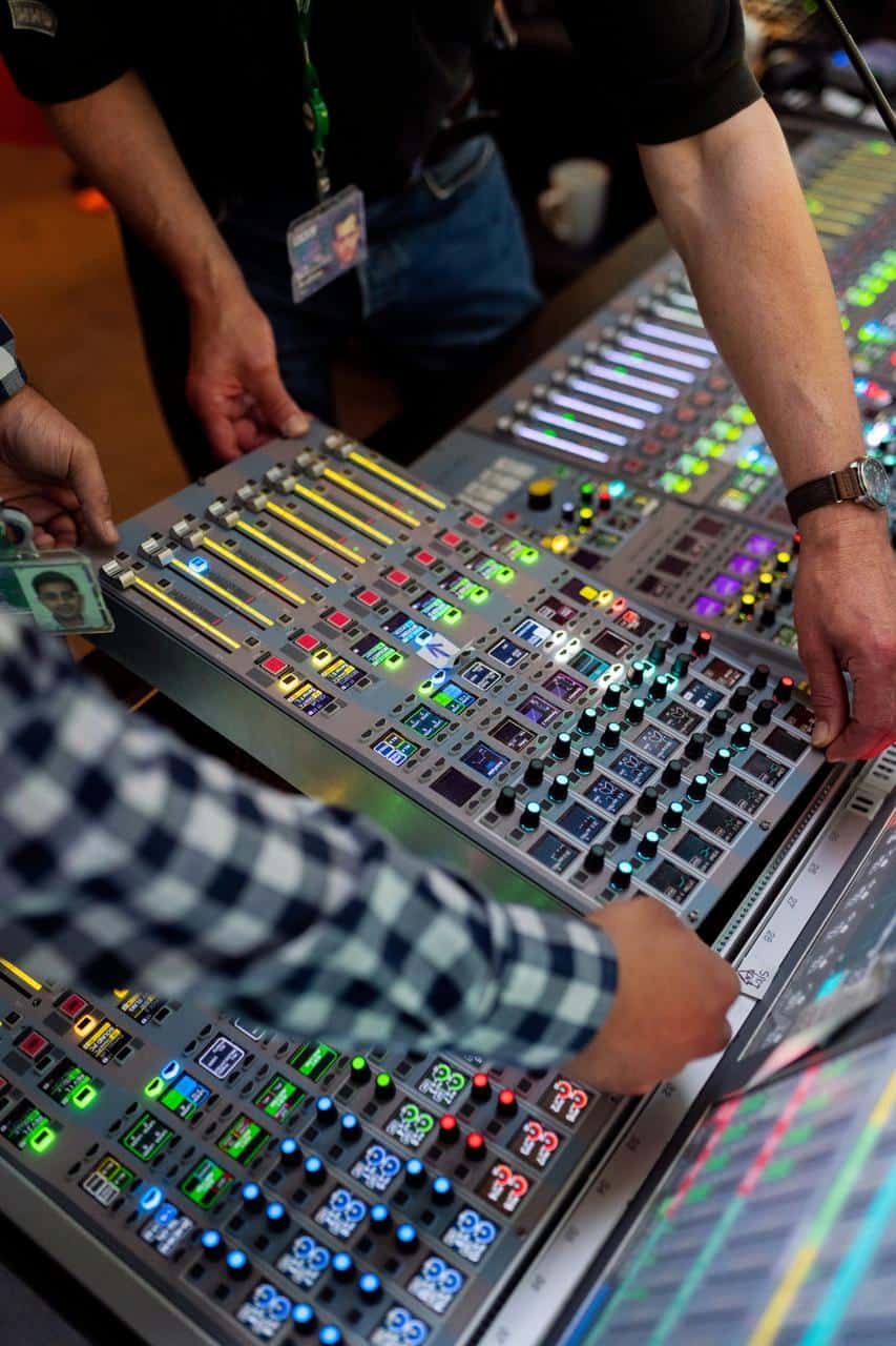 Hands adjusting controls on a professional audio mixing console—representing careers in sound engineering, broadcasting, and live audio mixing.