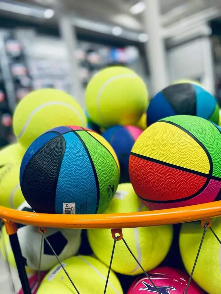 Close-up of colorful basketballs and tennis balls in a sports store, representing the dynamic environment of a sporting goods sales representative role.