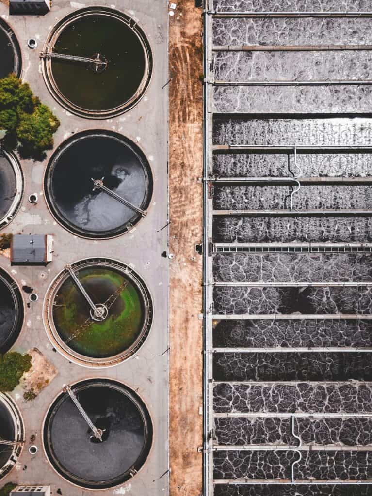 Aerial view of water treatment plant operations showing circular and rectangular filtration tanks used in public water purification.