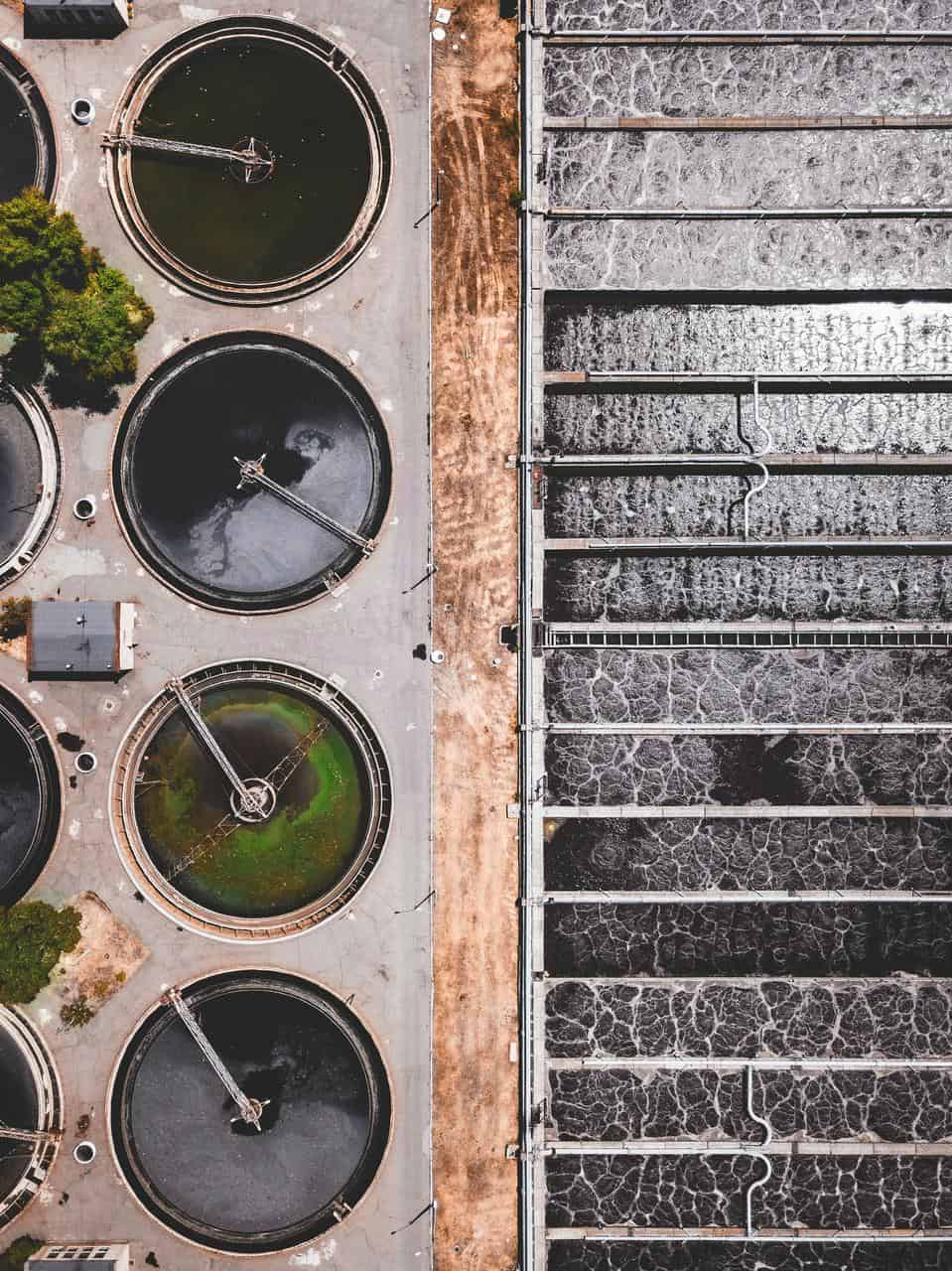 Aerial view of water treatment plant operations showing circular and rectangular filtration tanks used in public water purification.