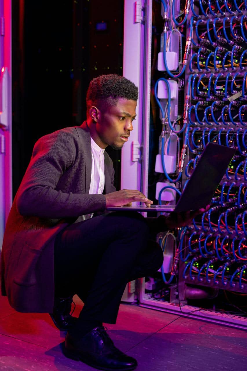 5G network engineer configuring server rack in data center with laptop