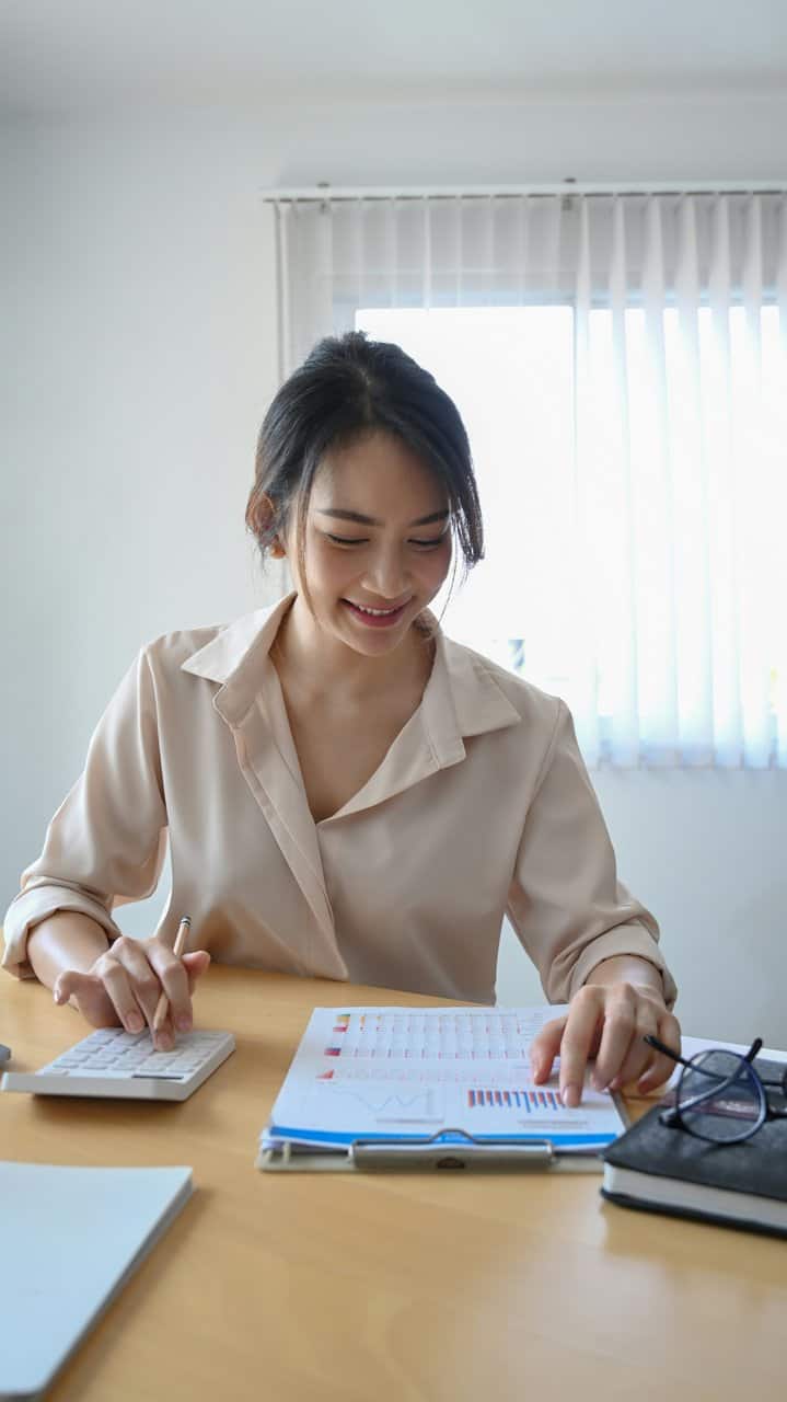 Young bookkeeper analyzing financial data and using a calculator at desk
